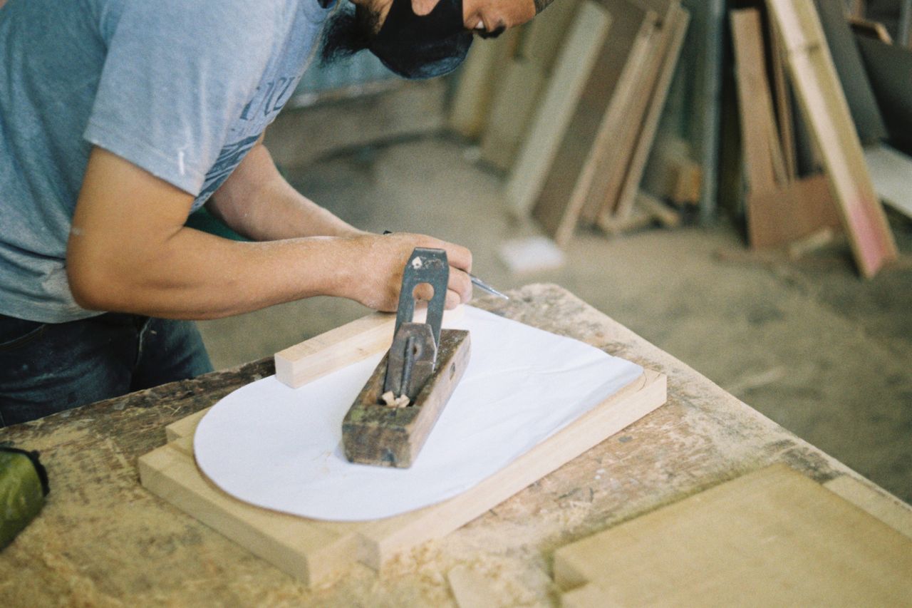 Ébéniste travaillant à l'atelier avec du bois brut et des outils traditionnels